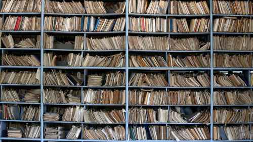 shelves full of files in a messy old-fashioned archive